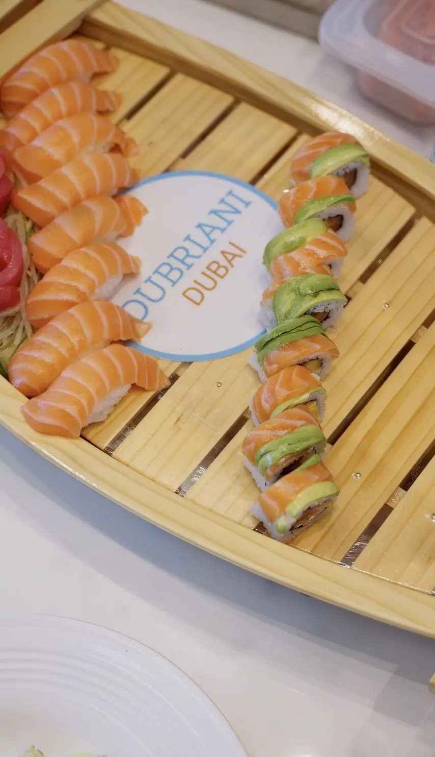 Assorted sushi rolls and salmon sashimi served on a wooden board aboard a luxury yacht in Dubai