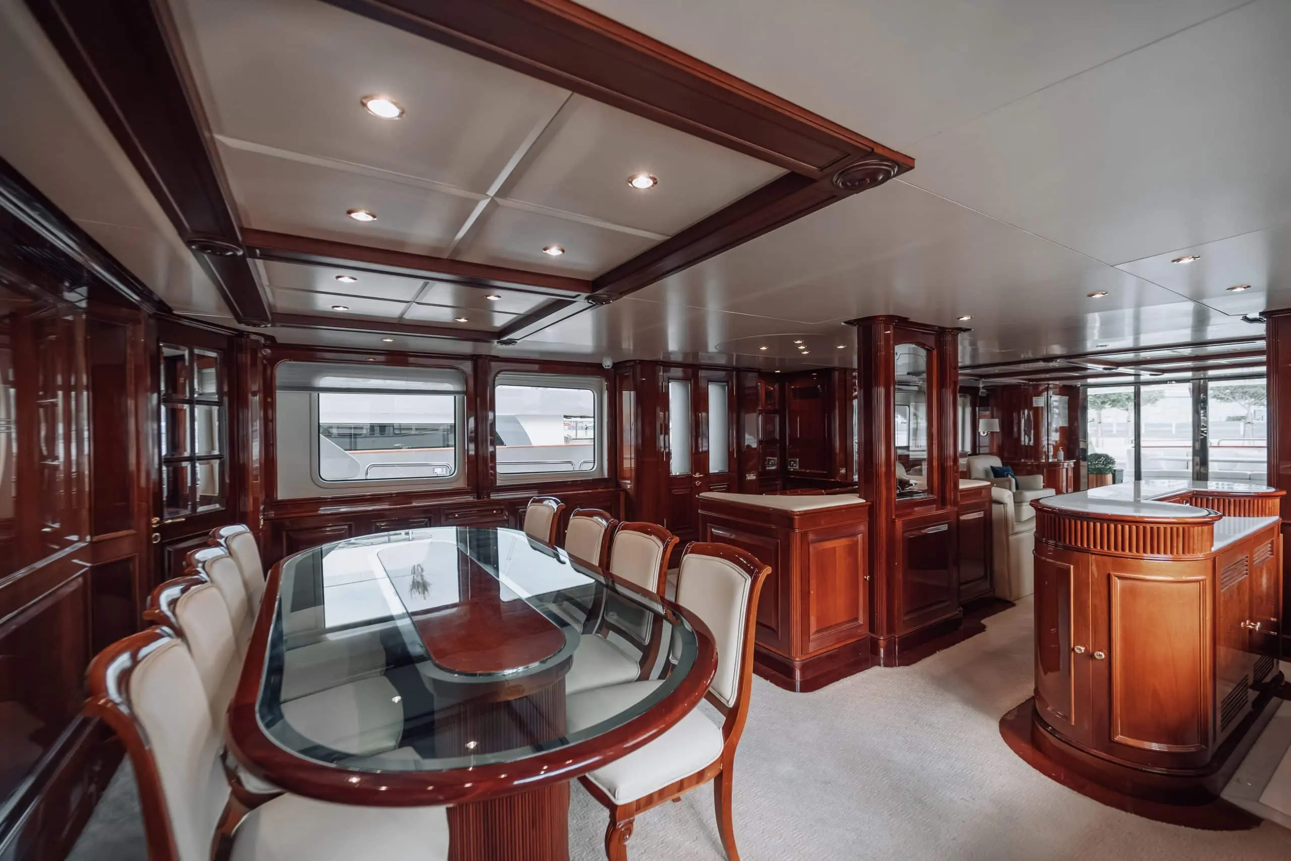 Royal Mirage yacht interior featuring luxury wood-paneled dining area with glass table and leather chairs