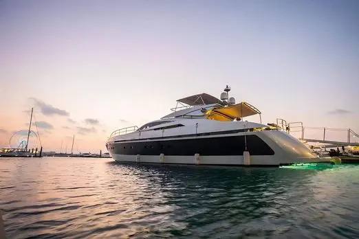 Baglietto 110 yacht front quarter view at sunset with warm reflections on calm sea waters