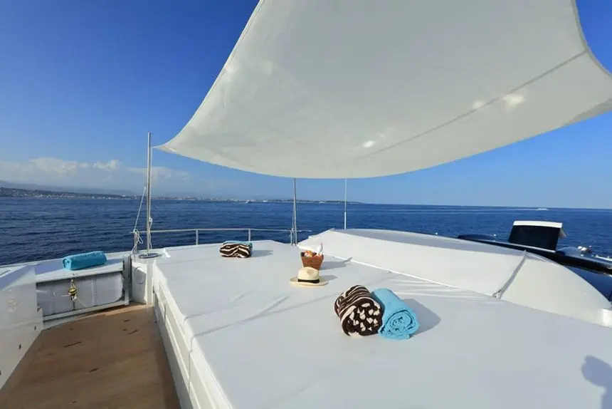 Baia 100 foredeck sunpad with towels beneath canvas shades
