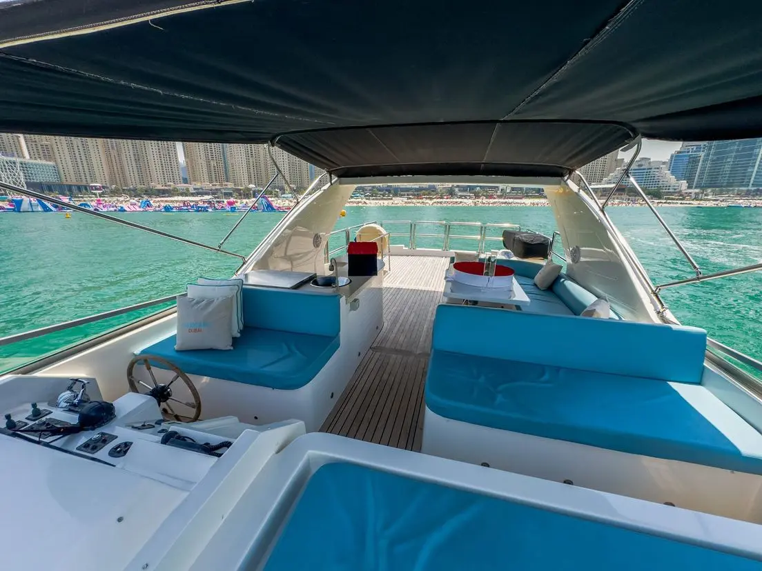 Cabo 77 yacht upper deck lounge with blue seating and shaded canopy in Dubai Marina