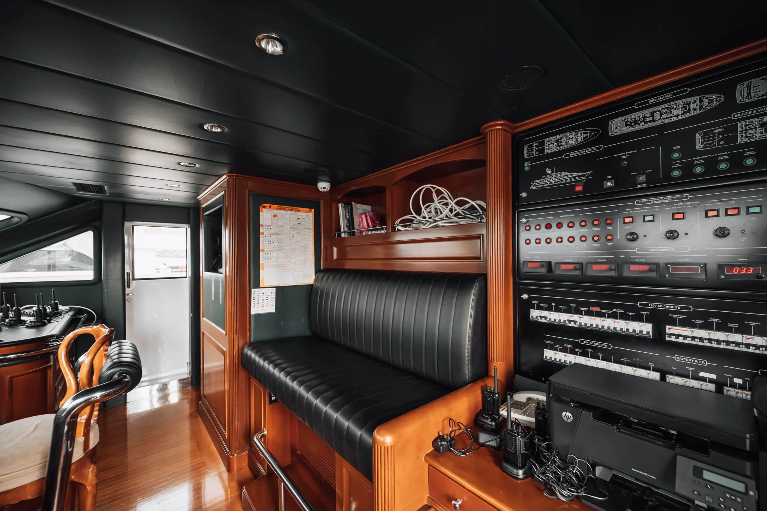 Luxury yacht navigation room with advanced control panels, communication devices, and wooden interiors.