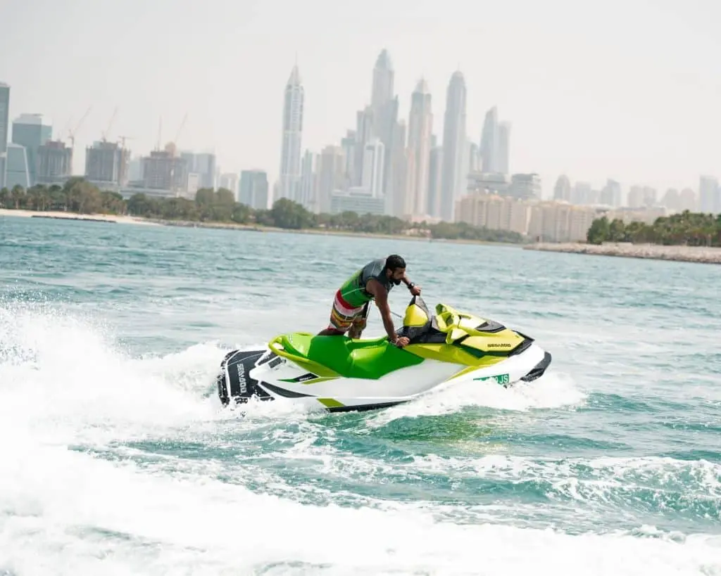 Jetski rider speeding across turquoise water with Dubai skyline in the background