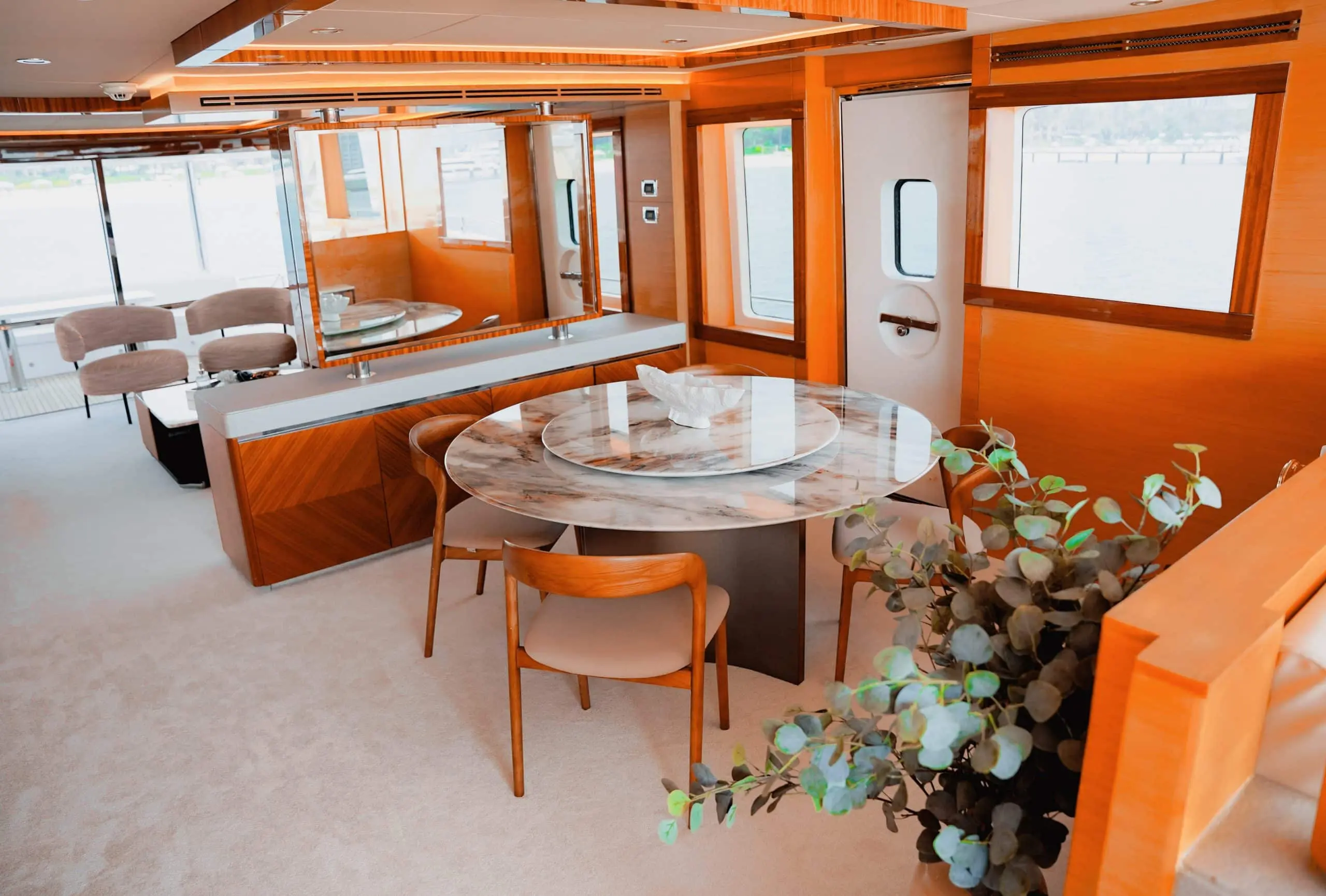 Luxury interior dining area onboard Carina 75 yacht with round glass table and wooden finishes