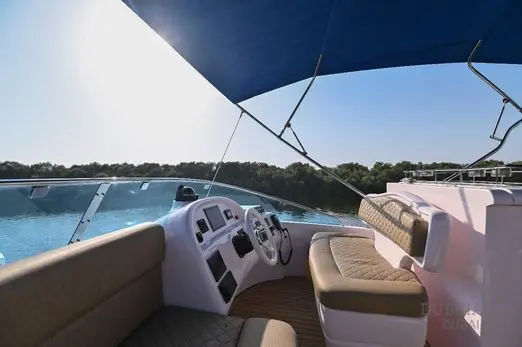 Novia 55 flybridge helm station under a navy bimini canopy with beige bench seating and teak decking