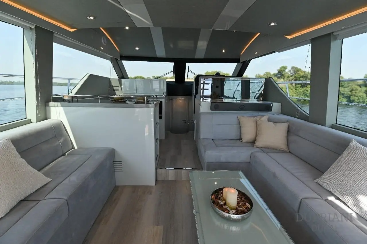 Novia 55 salon interior with facing grey sofas, glass coffee table and oak flooring