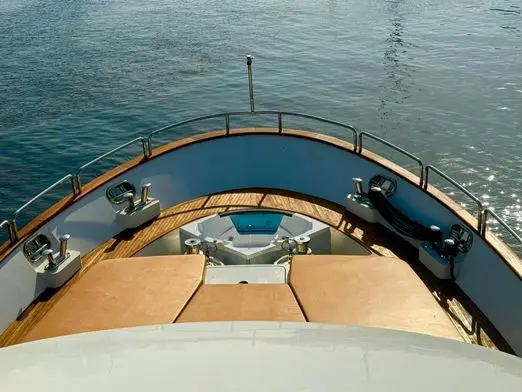 Side deck of the Lamborghini 63 speed yacht cruising with its wake and the Dubai coastline in the haze