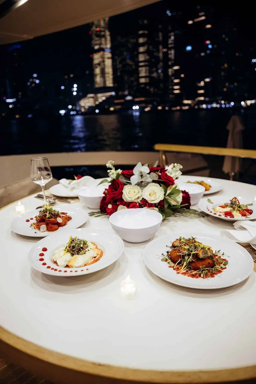 luxury yacht dinner setup at night with gourmet dishes and city skyline