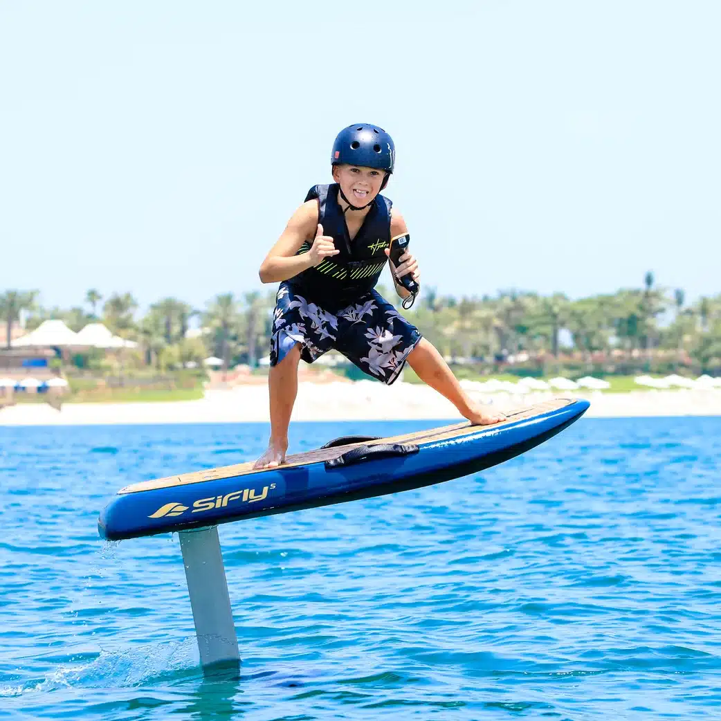 Child riding an efoil board on blue water in Dubai