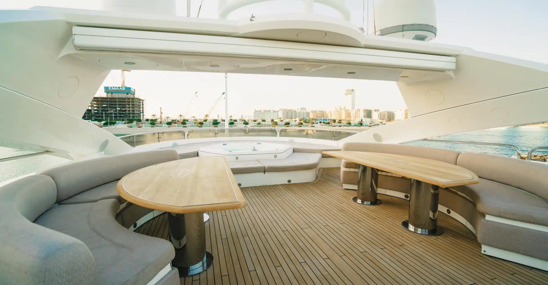 Aft deck lounge area on Sunseeker 131 yacht with teak flooring and dining tables