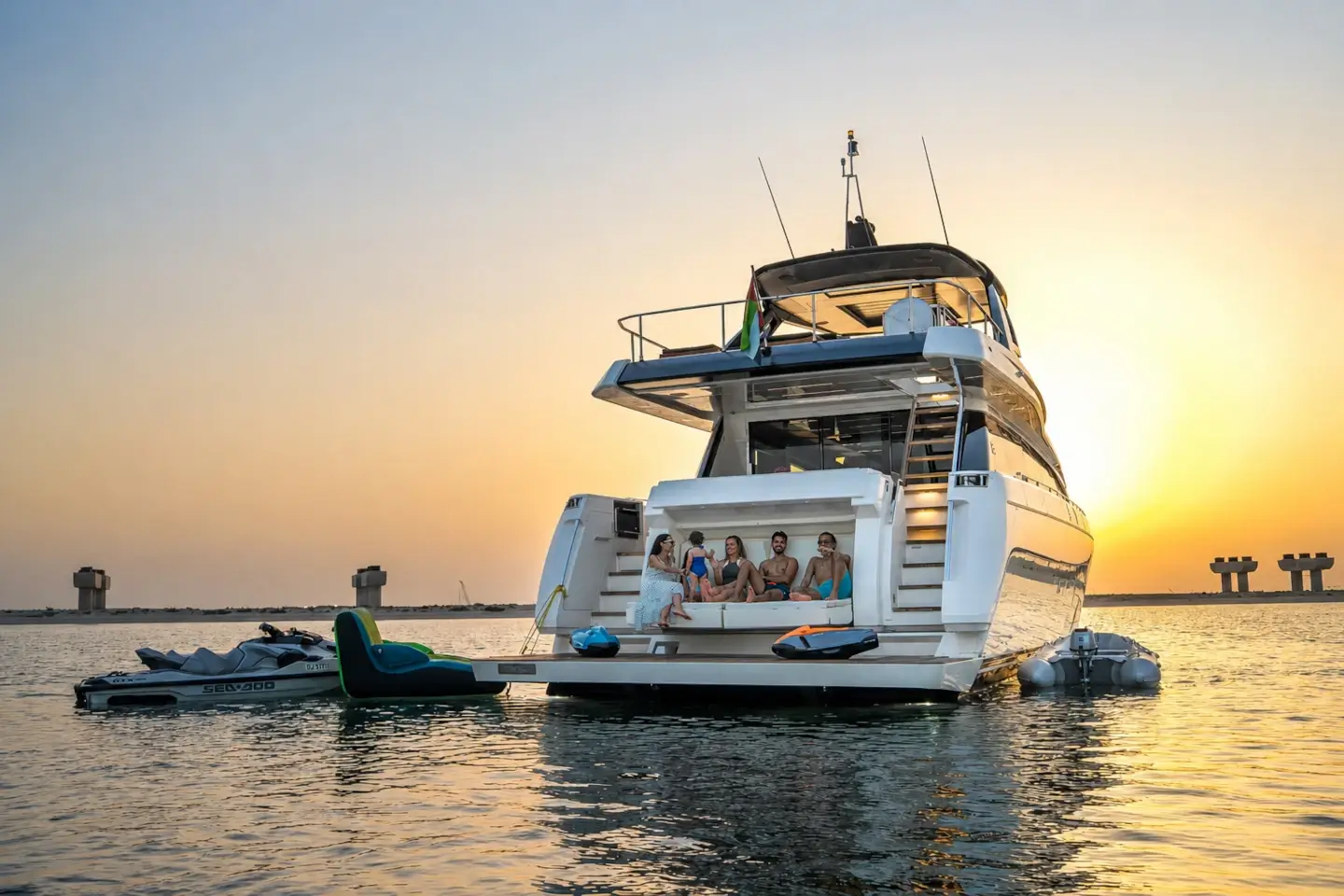 Ferretti 780 at anchor at sunset with jet ski and water toys off the stern