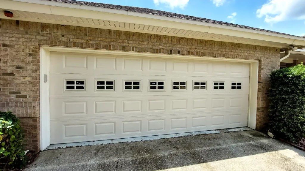 off-white or almond-colored traditional raised-panel sectional garage door