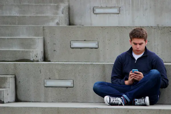 child sitting alone with cell phone symbolizing child refusing to visit with a parent