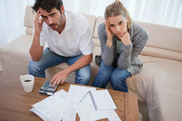 couple sitting with papers on desk frustrated symbolizing dividing separate finances