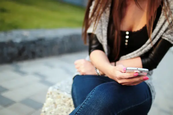 woman sitting outside staring at phone symbolizing internet addiction