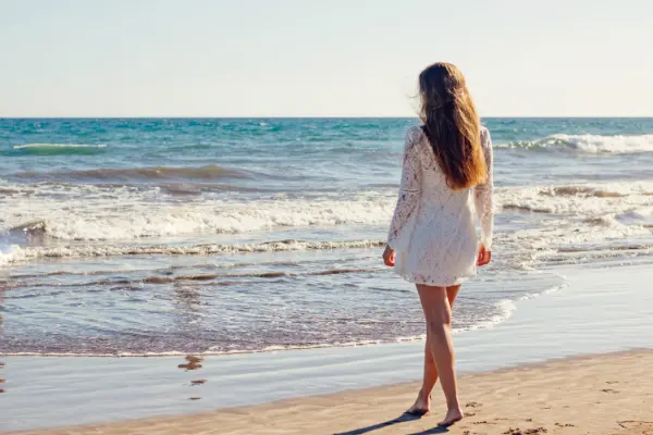woman walking alone on beach to symbolize end of a relationship