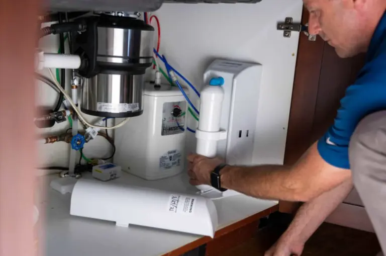 Person installing a water filtration system under the sink, part of Installing a Water Filtration System in Asheville Homes.