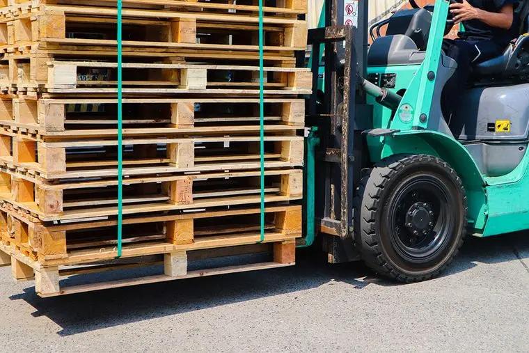 A forklift delivering a banded stack of pallets