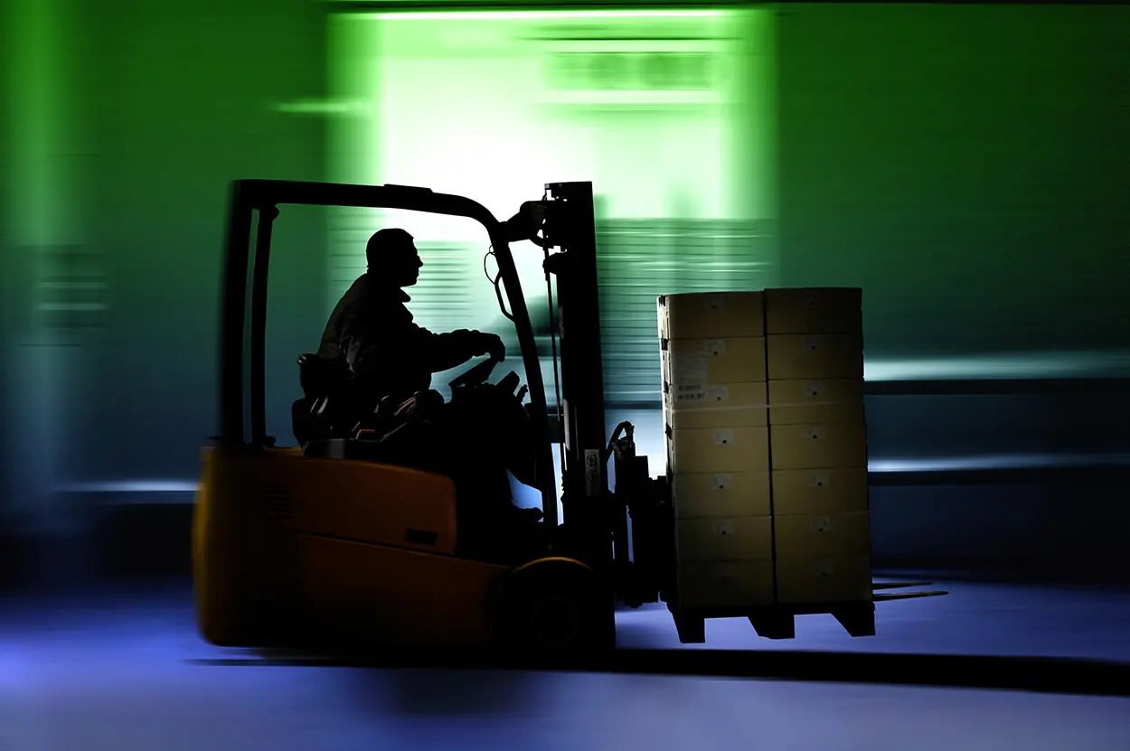 A forklift operator moves a pallet of boxes.