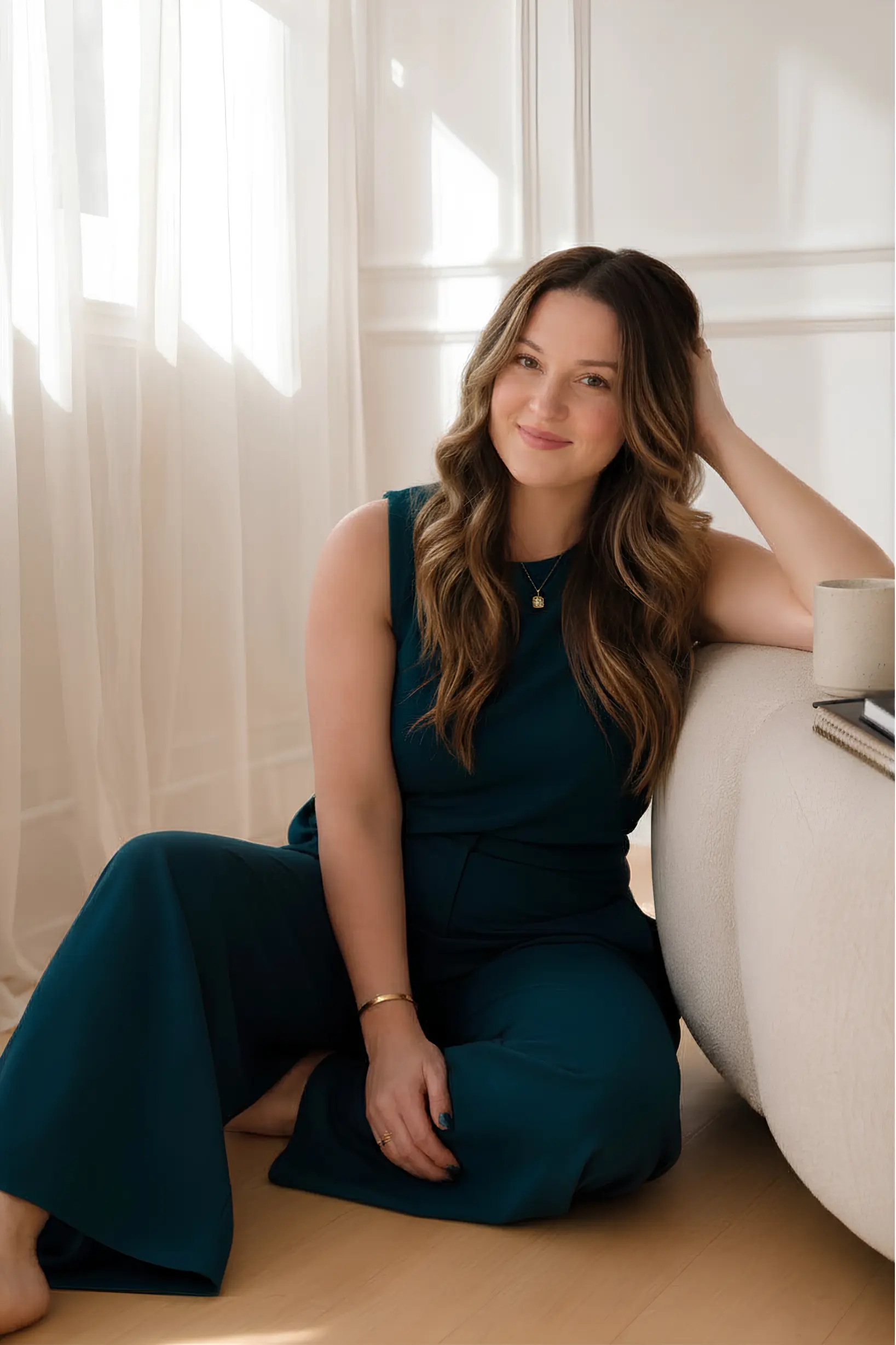 Marybeth Welty, who builds AI employees for women entrepreneurs, sitting in a sunlit room in a teal jumpsuit