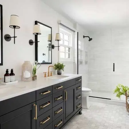 Elegant bathroom vanity with black cabinetry, gold handles, and stylish lighting fixtures.