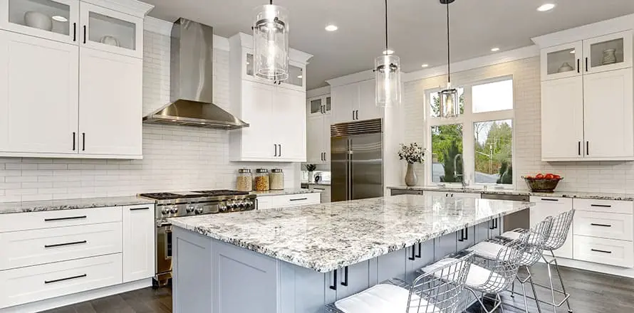 Modern white kitchen with granite countertops and stainless steel appliances.