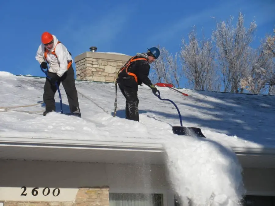 Crew clearing snow from a residential roof