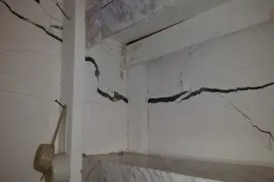 Foundation settlement cracks spreading across a concrete block basement wall in a Pittsburgh-area home