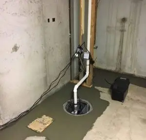 Interior basement drainage system with sump pump and drainage pipes installed in a concrete floor, showcasing components essential for preventing water accumulation and foundation damage.