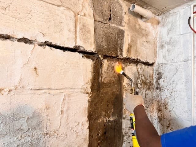 Bowing basement wall crack repair with torch and sealant, basement wall stabilization solutions.