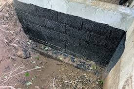 Sump pump installation in basement wall with waterproofing sealant, demonstrating interior waterproofing solution for moisture prevention.