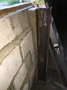 Reinforced foundation wall with steel support beams and crack repair, addressing structural damage.