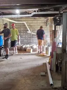 Highlander Waterproofing team installing basement drainage system and dehumidifier.