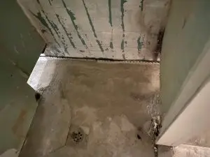Damp basement floor and walls showing water intrusion and potential damage, highlighting the need for