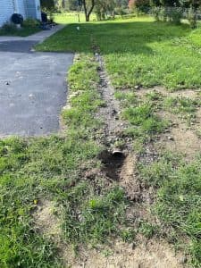 French drain installation showing a trench with gravel and a perforated pipe, designed for effective water management in a soggy backyard.