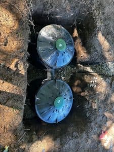 French drain installation in yard, drainage pipes and gravel for water management.