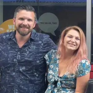 Two smiling individuals posing together, showcasing community spirit and connection, in a setting that reflects a vibrant cultural event related to local charitable initiatives.