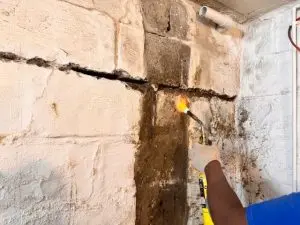 Bowing basement wall with horizontal crack and repair work in progress, demonstrating foundation structural failure.