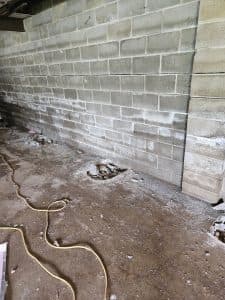 Water-damaged retaining wall showing efflorescence and soil accumulation, illustrating waterproofing necessity.
