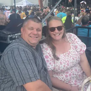 Smiling couple enjoying the Rock Reggae Relief event, surrounded by a lively crowd, showcasing community spirit and celebration.