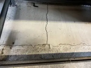 Cracked concrete floor illustrating foundation issues, emphasizing the importance of inspections and maintenance for homeowners.