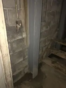 Steel pier supporting foundation wall and preventing settlement.