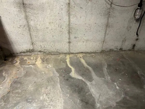 Water stains and discoloration on a basement floor, indicating moisture issues and potential need for basement waterproofing.
