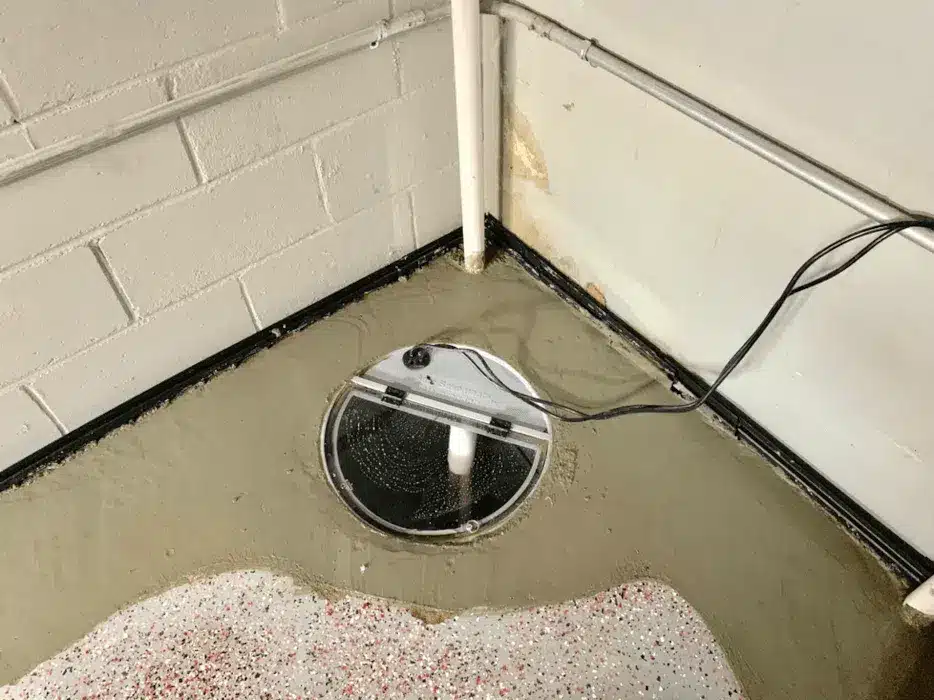 Basement sump pump system installed in sealed pit with interior drainage connection