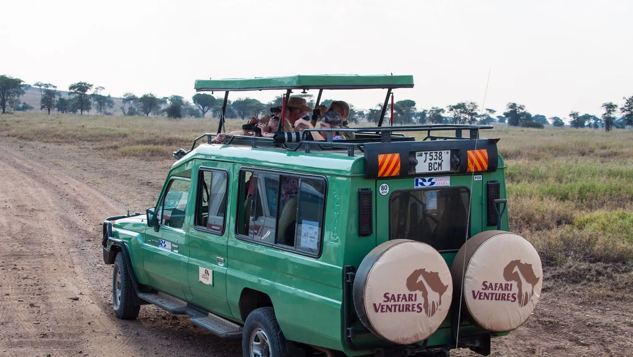 travelers on a guided African safari vehicle in open savannah, representing a private vs group safari