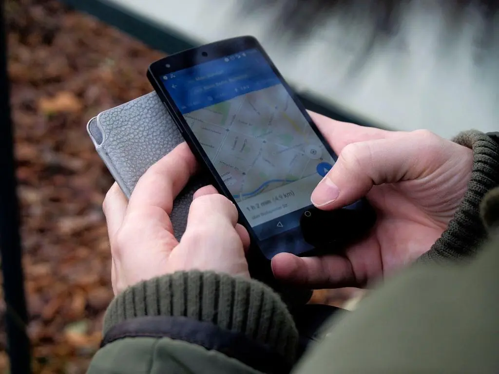 Person using GPS map on a smartphone, emphasizing the need for accurate NAP info to boost local SEO for landscapers