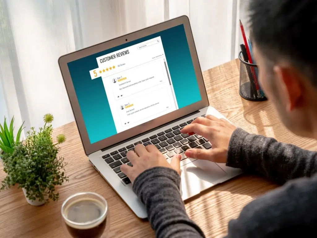 Person reading 5 star customer reviews on a laptop, highlighting the value of online reviews for landscaping businesses