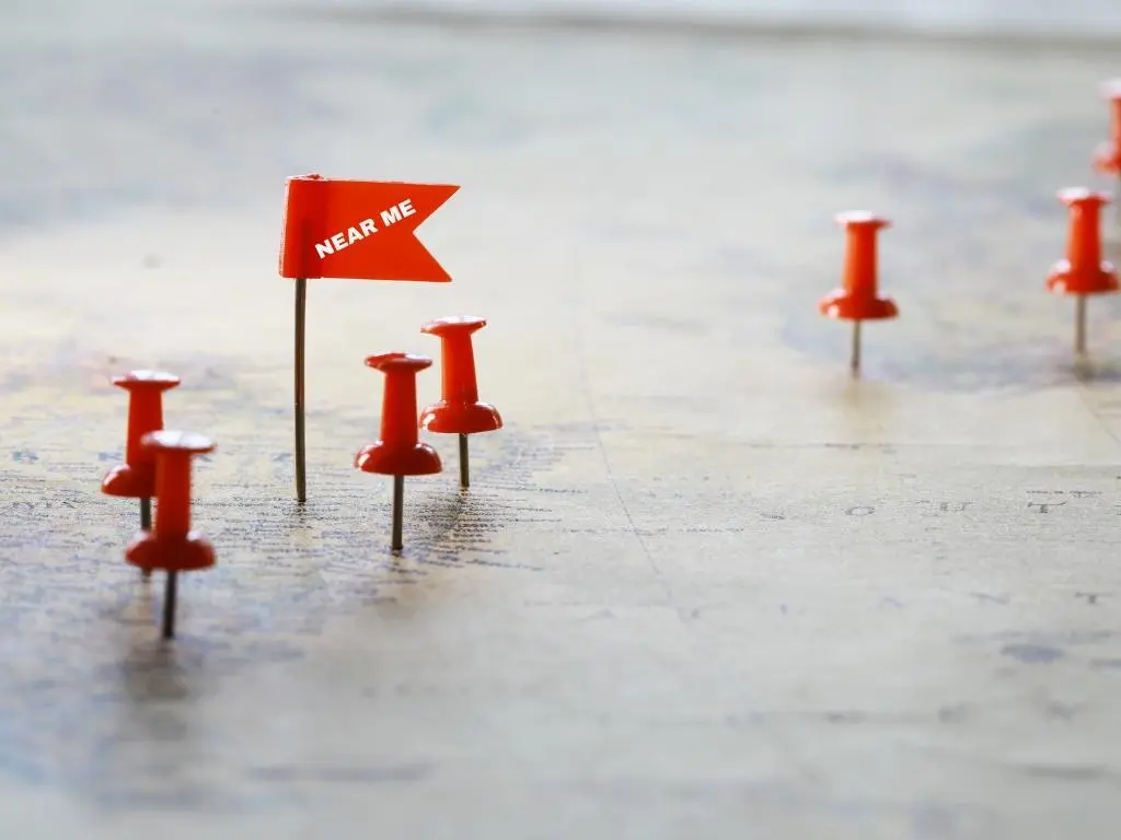 Map with red push pins and a “Near Me” flag, representing local SEO strategies for landscaping businesses to rank nearby