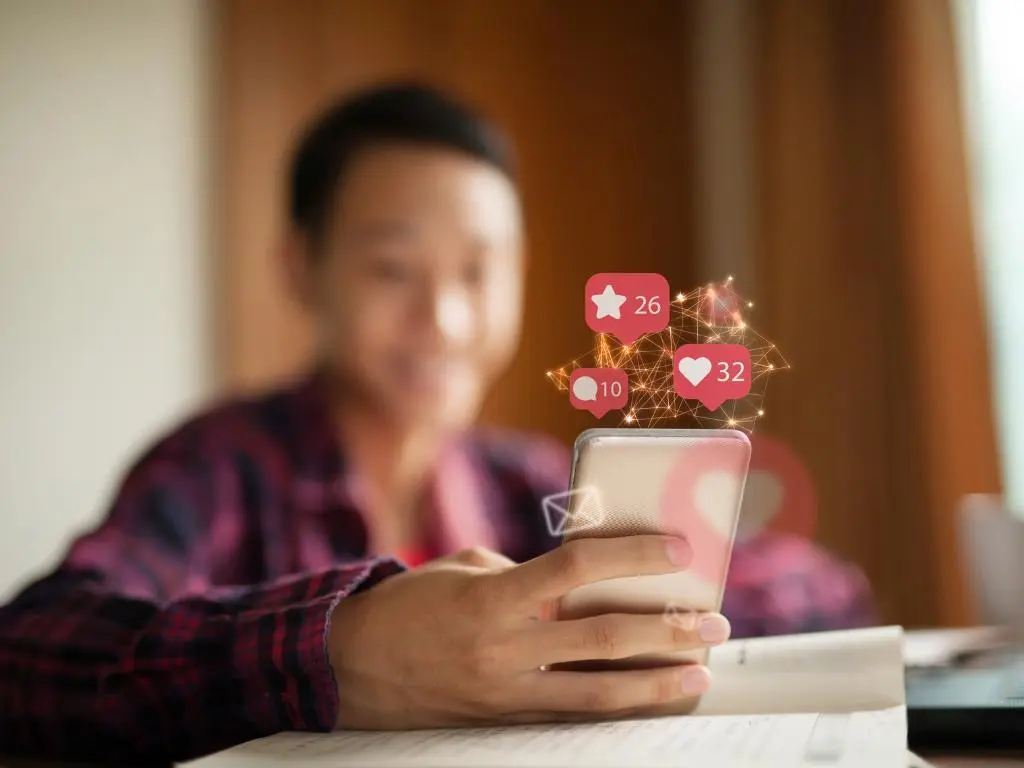 Person using a smartphone with social media icons, highlighting social media's role in off page SEO for landscapers