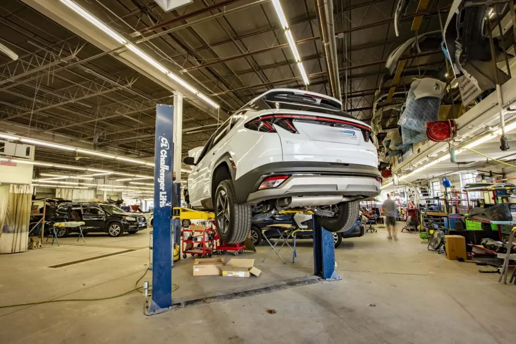 Collision Center 1 auto body repair facility in Golden Valley, MN, with a white SUV raised on a vehicle lift.